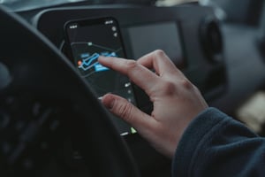 Conductor utilizando GPS en dispositivo móvil para planificar rutas logísticas y optimizar entregas en tiempo real.