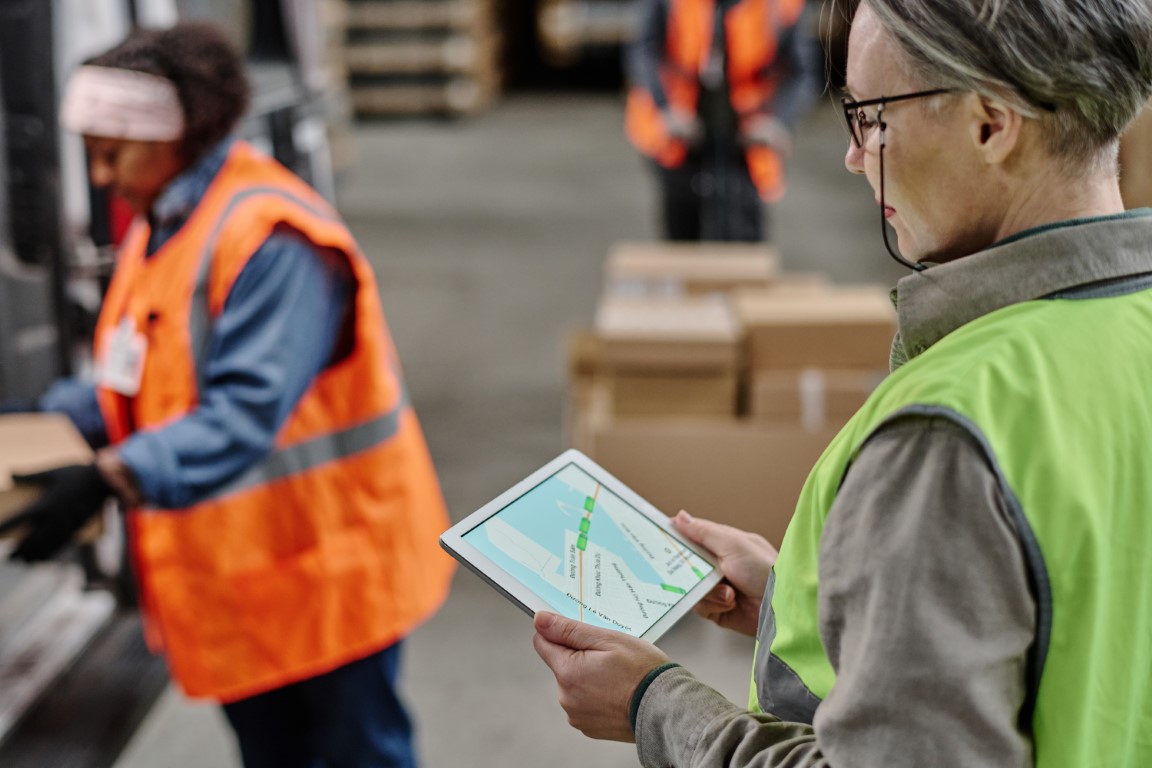 Supervisor logístico usando tablet con mapa digital para gestión de entregas en tiempo real.