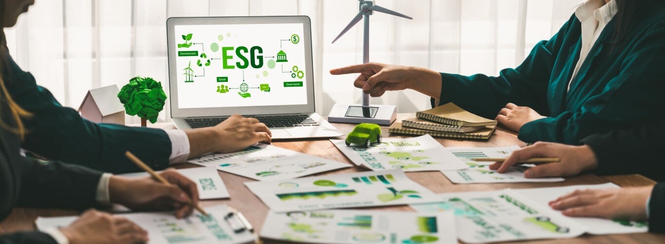 Empresarios analizando estrategias ESG en sostenibilidad, medio ambiente y gobierno corporativo con gráficos y laptop en reunión.